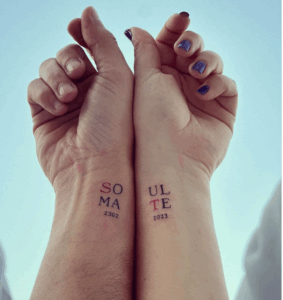 Couple's wrists displaying matching tattoos reading "SOULMATE" with the years 2302 and 2023, symbolizing love and commitment.